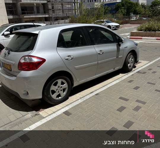 מכונית כסופה חונה בחניה על רקע בניינים